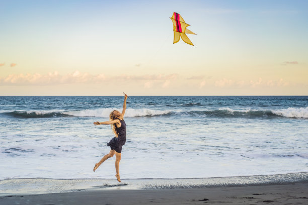 一位年轻女子在海滩上放风筝。梦想，抱负，未来计划图片下载