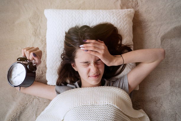 睡意朦胧的少女把闹钟关掉图片下载