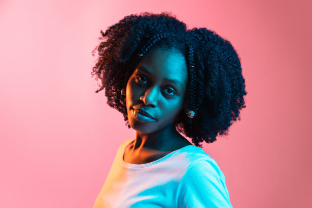 年轻美丽快乐的非裔美国女孩被孤立在霓虹灯的粉红色背景下。图片下载