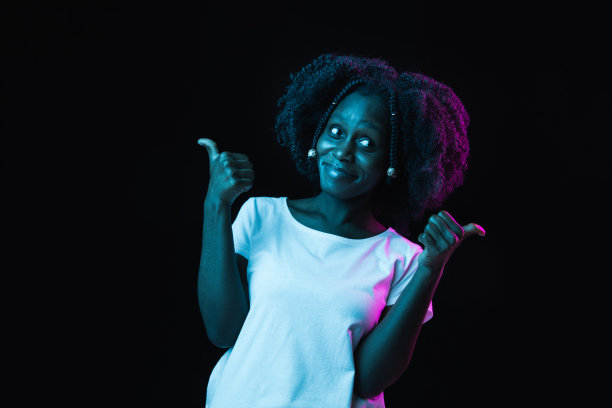 年轻美丽的非裔美国女孩孤立在黑暗的背景霓虹灯图片下载