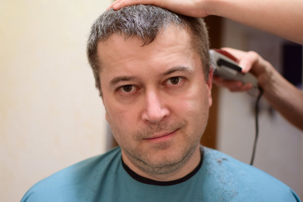 一名男子正拿着理发器对着镜头坐着。也许在家里被封锁了图片下载