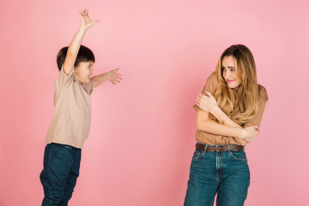 年轻的女人和小男孩，母亲和儿子孤立在粉红色的背景下。图片下载