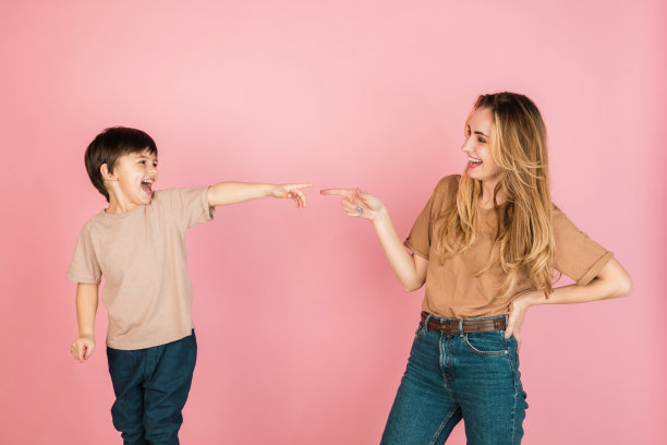 年轻的女人和小男孩，母亲和儿子孤立在粉红色的背景下。图片下载