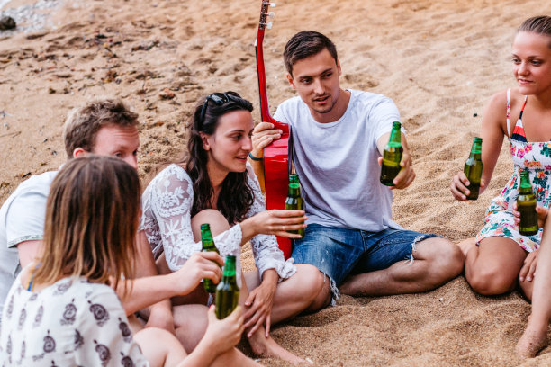 朋友们在海滩上玩吉他，喝啤酒图片下载