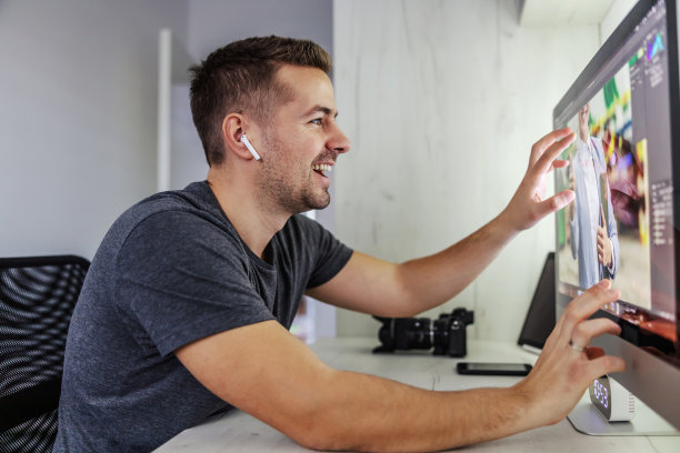 快乐的年轻人通过网络耳机与同事交流，他们谈论虚拟现实项目和屏幕上照片的3D效果。摄影、设计、编程图片下载