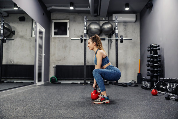 生活和耐力的体育运动与水壶重量。侧面的一个性感的女人穿着运动服和在健身房举重良好的形状。身体的稳定性，肌肉的灵活性和运动生活图片下载