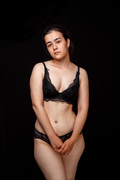 一个超重的年轻女人的肚子和身体。在一个孤立的黑色背景上。医学和美容的概念图片下载