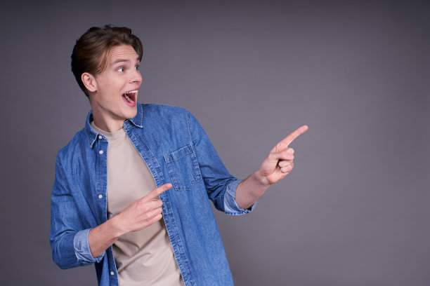 可爱开朗的年轻人穿着一件牛仔衬衫，手指在一边。图片下载