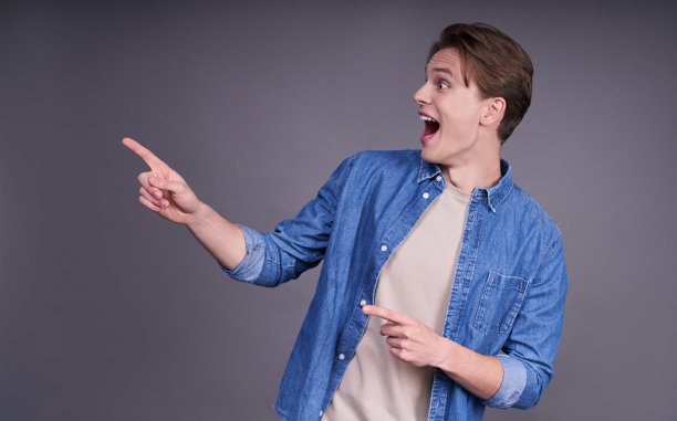 可爱开朗的年轻人穿着一件牛仔衬衫，手指在一边。图片下载