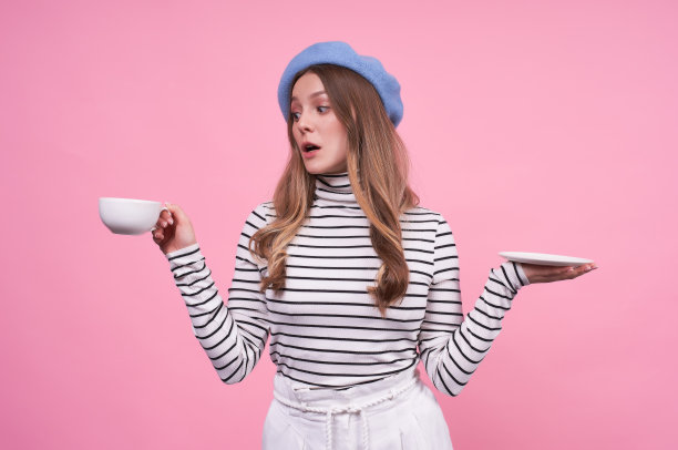 一个可爱的年轻女士的肖像戴着蓝色贝雷帽和一个杯子和碟子。图片下载