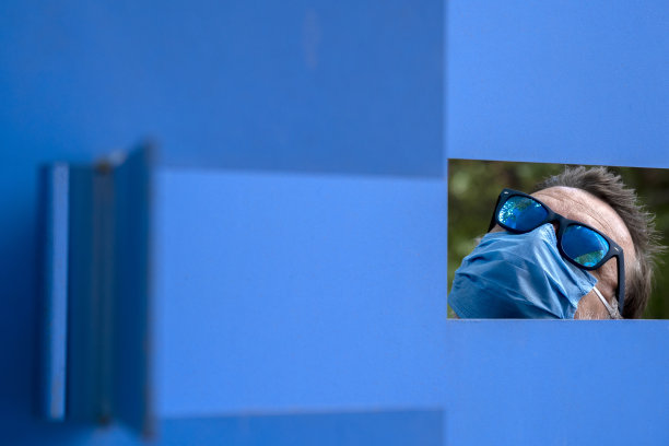 戴蓝色防护口罩、透过蓝色四边形框架看东西的年长男性肖像图片下载