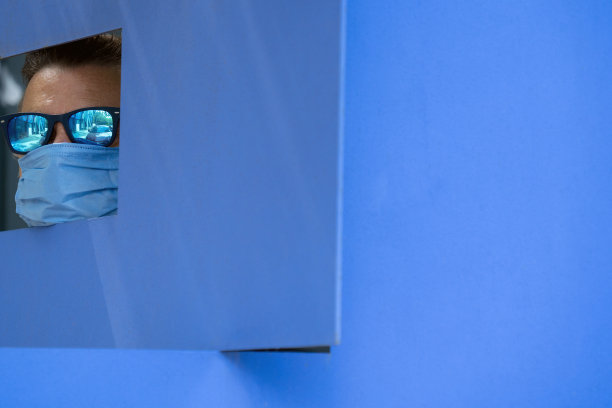 戴蓝色防护口罩、透过蓝色四边形框架看东西的年长男性肖像图片下载