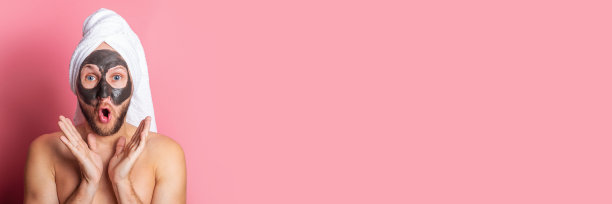 惊讶的年轻人与化妆面具在他的脸在粉红色的背景。护理,清洁。横幅图片下载