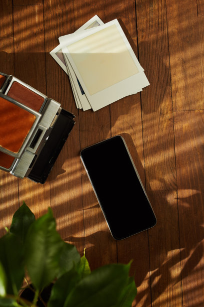 在下午的阳光下，桌子上平放的老式即时胶片相机、空白照片和智能手机的俯视图。潮人的物品图片下载