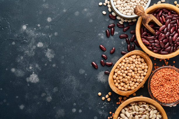 豆荚，红豆，鹰嘴豆，红豆和白豆混合在不同的碗里，在黑色的桌子上。饮食减肥和对抗胆固醇的概念。顶部视图与复制空间。图片下载