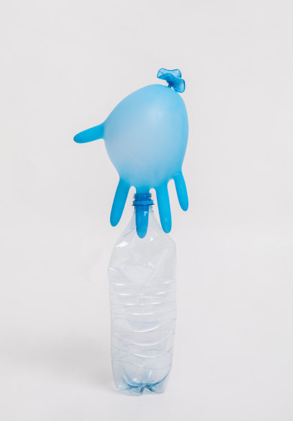 充气的蓝色橡胶医疗手套卡在空塑料瓶里图片下载