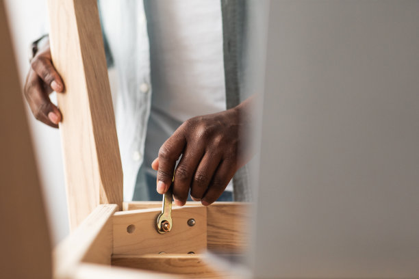 木工的概念。黑人组装木桌，用扳手拧螺丝，自己在家做图片下载