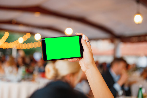 女人用智能手机拍下了派对的照片。空白屏幕图片下载