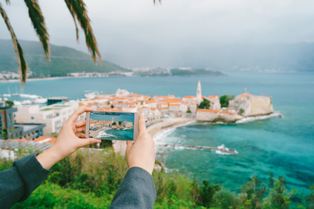 手拿智能手机，以黑山老城为背景的一张照片图片下载