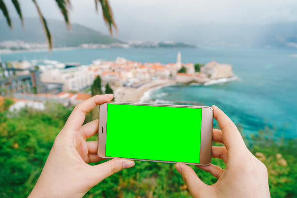 男人的手拿着一个黑屏的智能手机。背景是黑山的布德瓦古城。图片下载