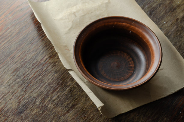 表格一张棕色的纸和一个空碗在一个划痕的木头表面。图片下载