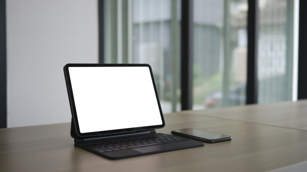 近距离观看电脑平板电脑与白色屏幕和智能手机在木制办公桌。图片下载