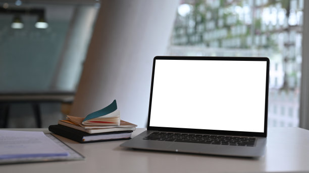 近距离观察模拟电脑笔记本电脑与空白屏幕和书在白色办公桌。图片下载