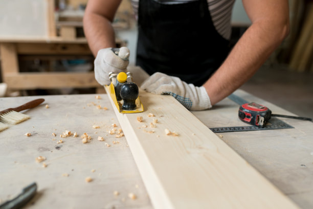 木匠在他的车间工作，他正刨着一块木头。木制家具的细木工工作。中小企业的概念图片下载