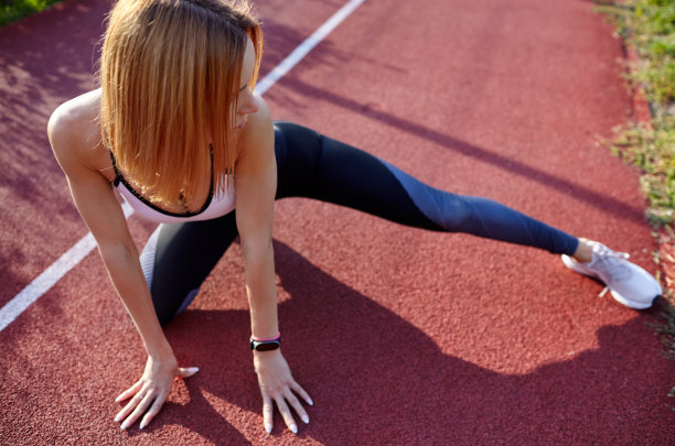 年轻的女运动员正在伸展身体，准备跑步。健身运动女性穿着时尚运动服在城市街道上锻炼图片下载