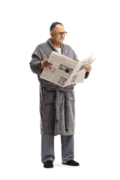中年男人穿着睡袍站立阅读报纸图片下载