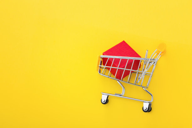 红盒子放在购物车里，黄色背景，平铺图片下载