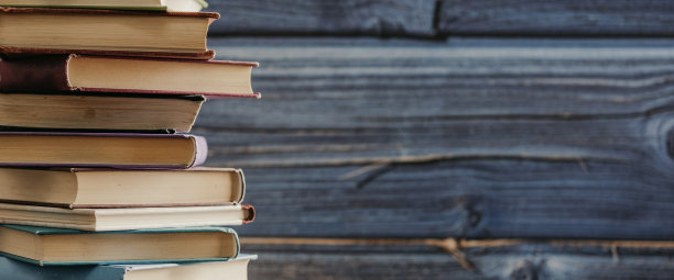 蓝色木头背景的木桌上放着一堆彩色封面的书。教育学习的概念图片下载