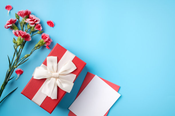 母亲节礼物。节日贺卡的设计理念，红色康乃馨花束在明亮的蓝色桌子背景图片下载