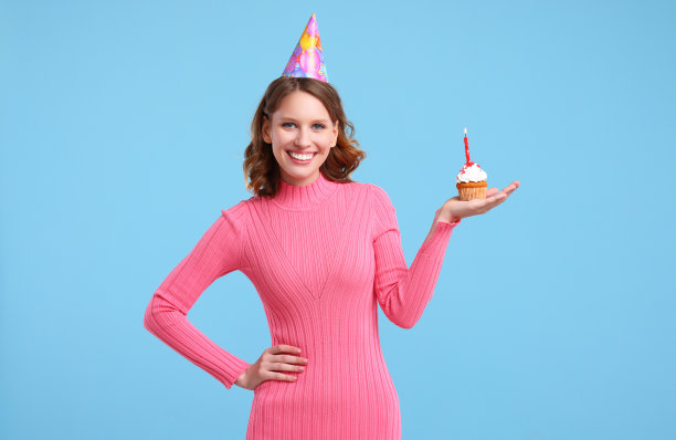 在生日庆典上，一个快乐的女人拿着纸杯蛋糕对着镜头微笑图片下载
