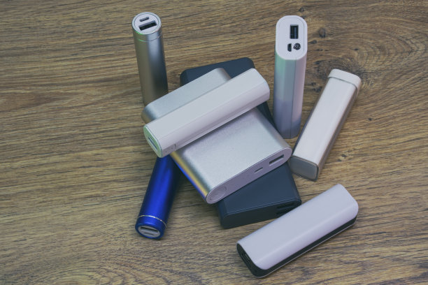 木桌上放着一套不同大小的电源盒。选择一个便携式充电器。图片下载