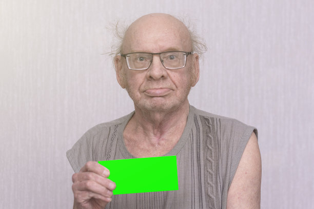 一个戴着眼镜、穿着灰色衬衫的退休秃顶老人手里拿着一片空白。图片下载