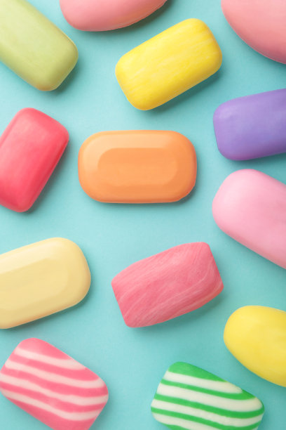 不同的肥皂装在不同的肥皂盘里。为了卫生和清洁用了很多固体肥皂。彩色的肥皂和残留物散落在蓝色的背景上。图片下载