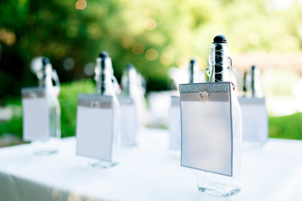 在绿色植物的背景下，铺着白色桌布的桌子上放着发光的瓶子图片下载