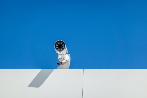 在明亮的蓝色天空的背景下，现代的观察相机在白色建筑的边缘图片下载