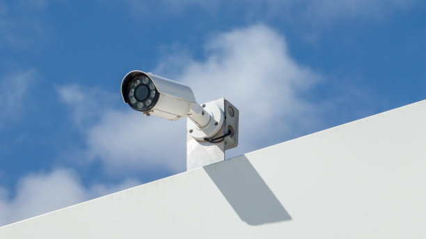 在明亮的蓝色天空的背景下，现代的观察相机在白色建筑的边缘图片下载