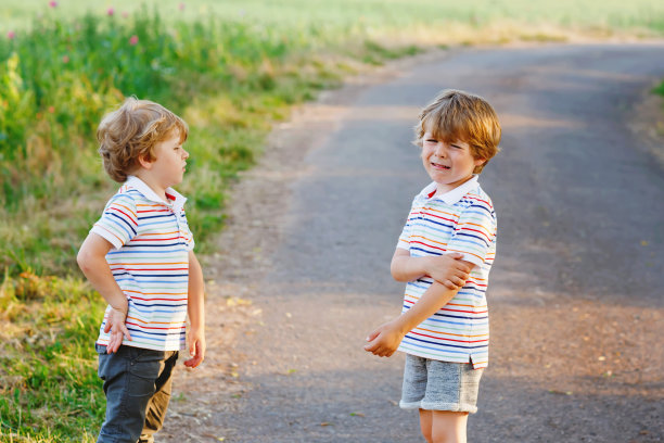 两个小男孩在打架。双胞胎，孩子们在户外争吵。兄弟姐妹之间的竞争。不幸的双胞胎。一个男孩在哭。图片下载