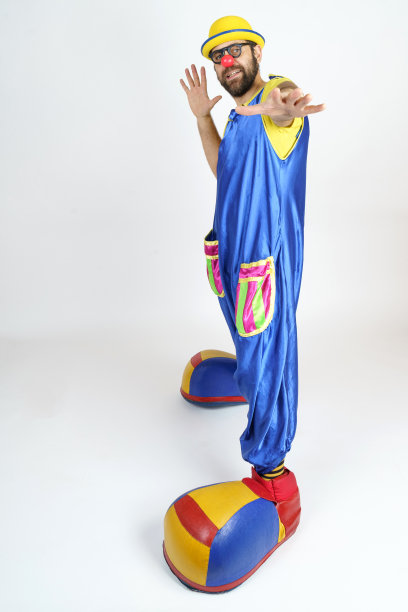 一个小丑穿着亮蓝色和黄色的衣服，戴着眼镜和帽子，他的手向前指。图片下载