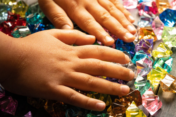 一个孩子的手抓着一块彩色的亚克力石图片下载