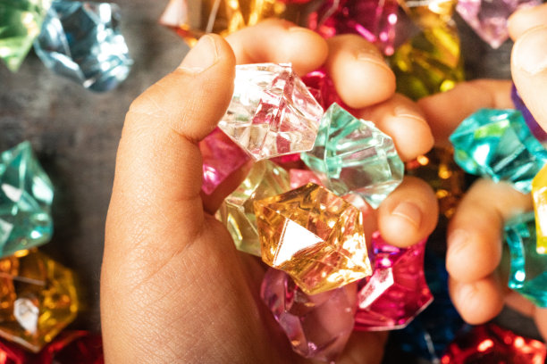 一个孩子的手抓着一块彩色的亚克力石图片下载