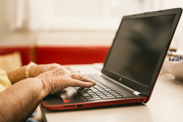 在家里使用数字笔记本电脑的资深女性。孤独的技术概念。老年人上网浏览。图片下载