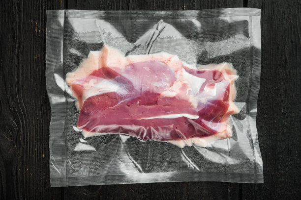 鸭胸真空密封，以黑色木桌为背景，俯视图平放图片下载