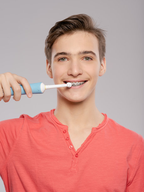照片中的年轻人正在照顾他的牙齿。口腔卫生。少年用牙刷刷牙。图片下载