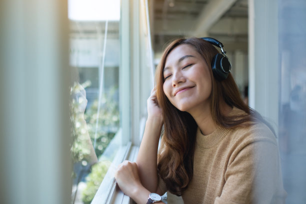 一位年轻美丽的亚洲妇女喜欢用耳机听音乐图片下载