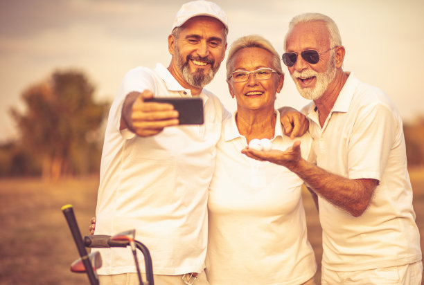 资深高尔夫球手使用手机和自拍。重点是背景。图片下载