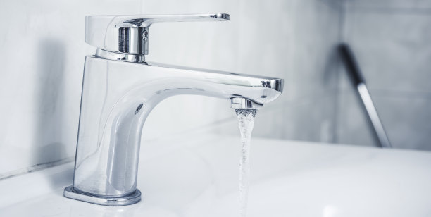 靠近水龙头和水滴。浴室内部有水槽和水龙头。图片下载